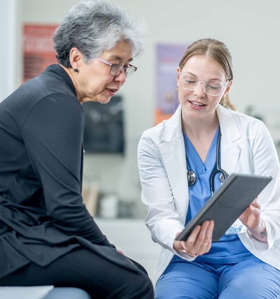 Healthcare provider showing a patient information on a tablet during a medical appointment.