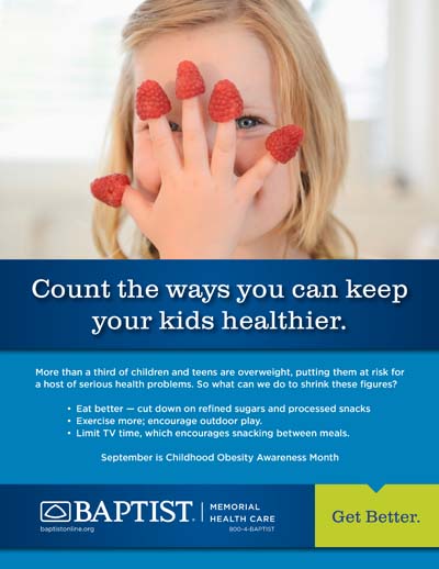 Child presses hand to face with raspberries on each fingertip, smiling in a bright indoor setting.